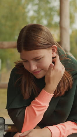 bearded man in medieval clothes talks emotionally sitting at table in yard. girl listens to friend and fixes hair smiling shyly on blurred background closeup