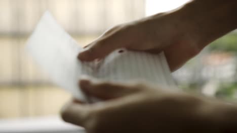 close up of a person opening a piece of paper and handing it to another person while closing it
