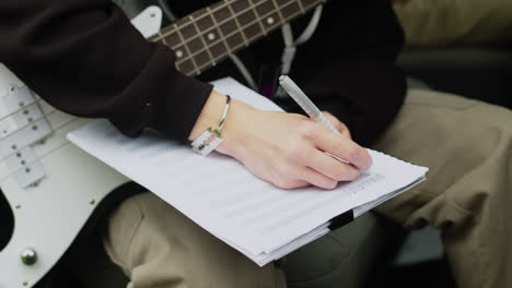 un homme tenant une guitare et des partitions de musique