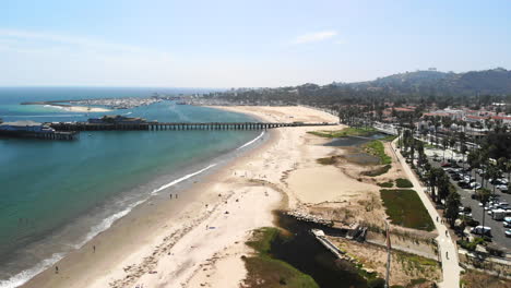 Aerial-shot-flying-out-over-the-beach-with-sail-boats-in-the-harbor-and-the-dark-blue-Pacific-Ocean-next-to-Stearn's-Wharf-pier-in-Santa-Barbara,-California