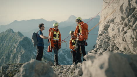 hiker meets three rescueclimbers in orange gears and casually talks with them