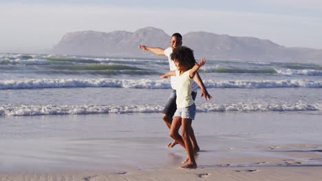 padre afroamericano y su hija jugando en la playa