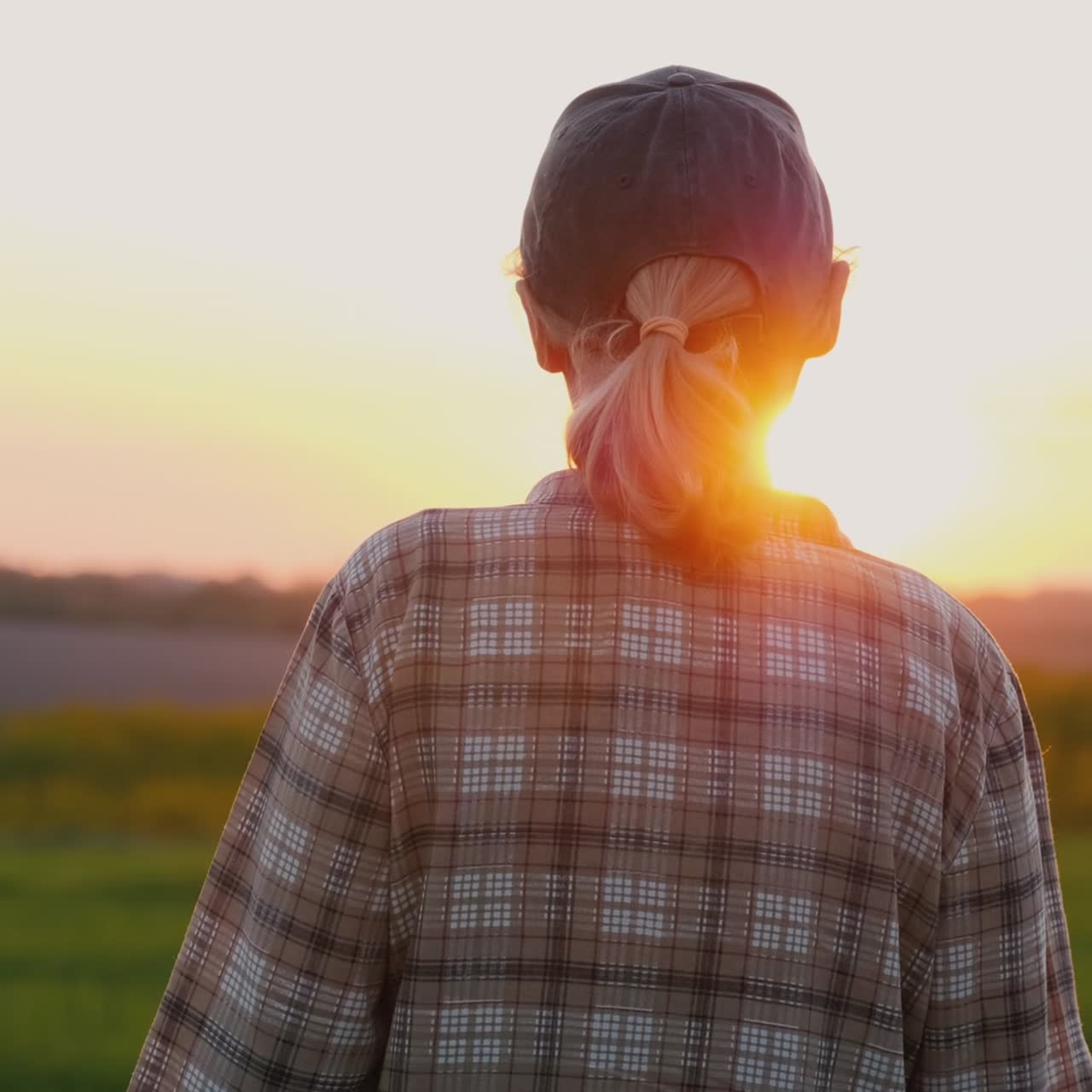한 여성 농부가 해질녘에 그림 같은 들판을 걷고 있다