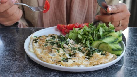 woman eating a mushroom and vegetable omelette