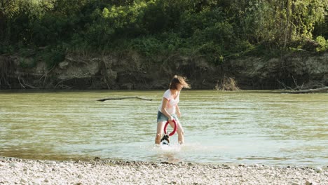 mujer jugando con el perro cerca del río