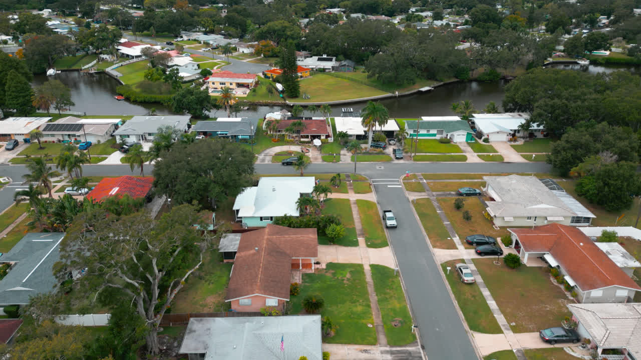 Suburban neighborhood with neat grid streets and lush greenery, along community lake, aerial flyover