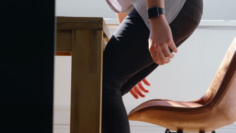 Side-view-of-young-caucasian-businessman-pulling-his-chair-forward-in-a-modern-office-4k