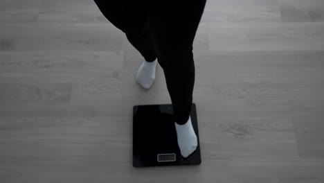 top down view of pregnant woman stepping on and off digital scale to check weight