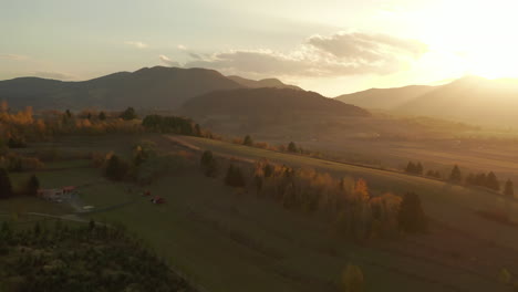 flyover above houses on scenic hillside towards peaceful valley at sunset