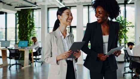 professional businesswomen collaborating and laughing in a modern office