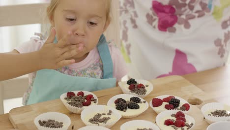 Süßes-Kleines-Mädchen,-Das-Beeren-Auf-Muffins-Setzt