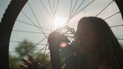 lady gently touching bike wheel with a warm smile as sunlight reflects off her and the rotating wheel, creating a magical moment, the blurred background adds to the serenity