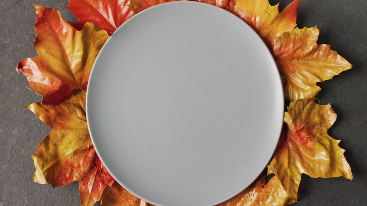 Video of plate with autumn leaves and decoration lying on grey surface