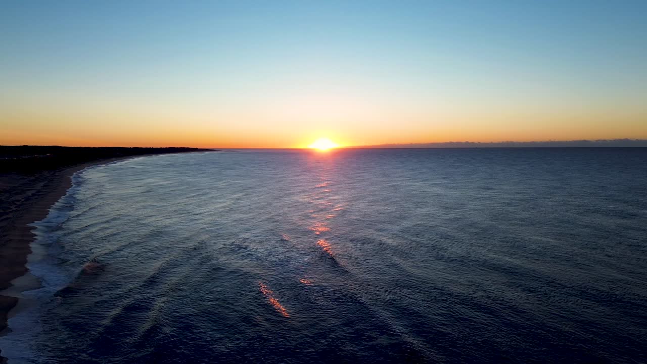 Drone aerial landscape of golden orange sunrise on horizon coastline with waves breaking on coastal town sandy beach headland The Entrance Central Coast Australia travel holidays nature tourism