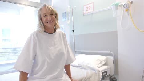 portrait of happy caucasian female senior patient with prosthetic leg sitting in the bed at hospital