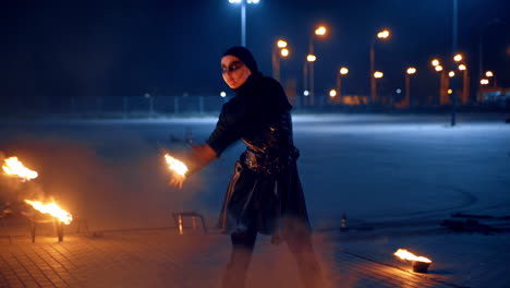 a dancing couple performing fire show outdoors at night. artists move with burning props in hands.