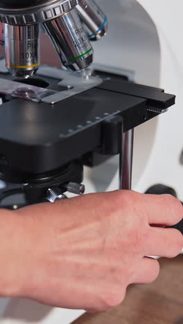 Scientific laboratory microscope examining drop. Close up shot of sample slide and microscope with metal lens at laboratory