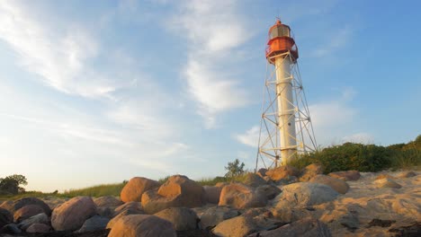 Beautiful-view-of-the-Pape-Lighthouse-on-a-calm-summer-evening-with-slow-moving-clouds-before-the-sunset,-wide-shot