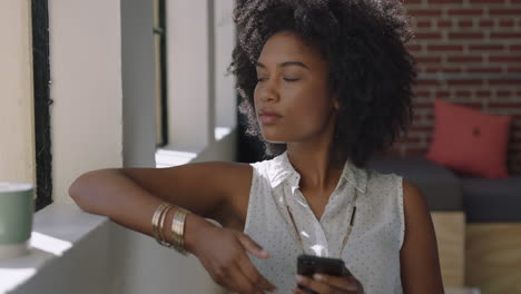 beautiful woman using smartphone at home browsing messages enjoying relaxed lifestyle looking out window planning ahead african american female texting on mobile phone