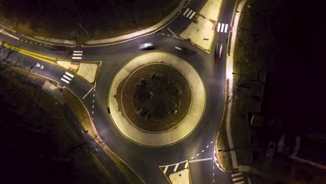rotating aerial timelapse birdseye traffic circle at night in the city with cars and lights
