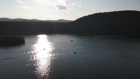 Boats-crossing-sun-reflected-over-water-on-Candlewood-Lake-in-Connecticut,-Northeast-USA-during-summer-season