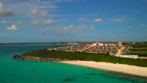 aerial pan shot of a new settlement inf ront of a tropical beach with turquoise water, miyakojima, okinawa, japan