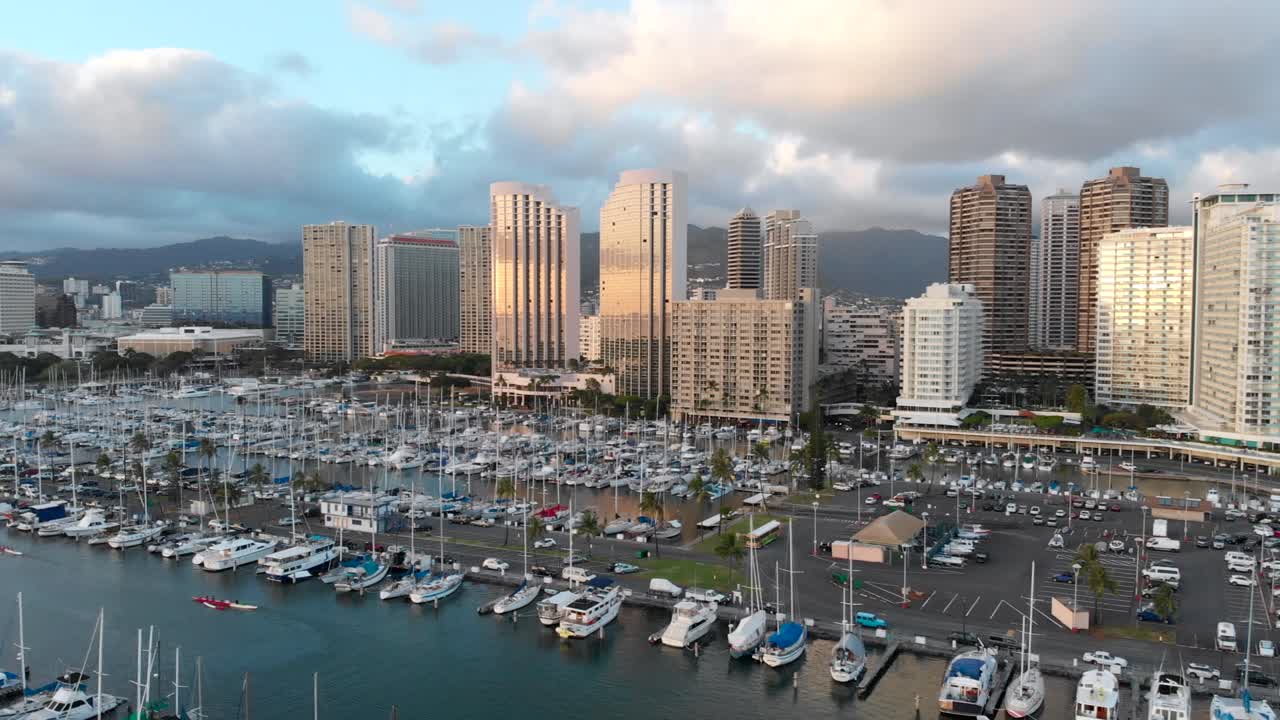 Aerial Pan over Boat Harbor, Kahanamoku Beach Lagoon, Waikiki Beach and Honolulu at Golden Hour, with Skyscrapers in the background