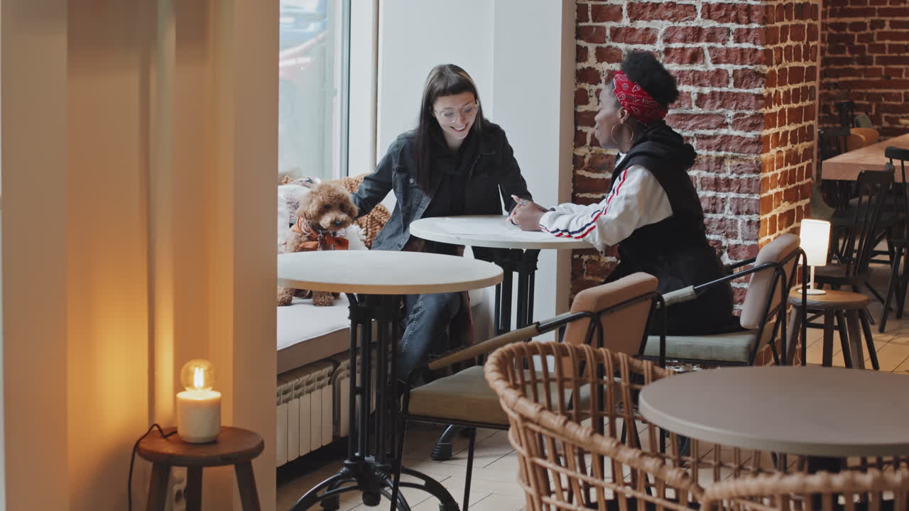 Lesbian Couple with Dog Chatting in Cafe
