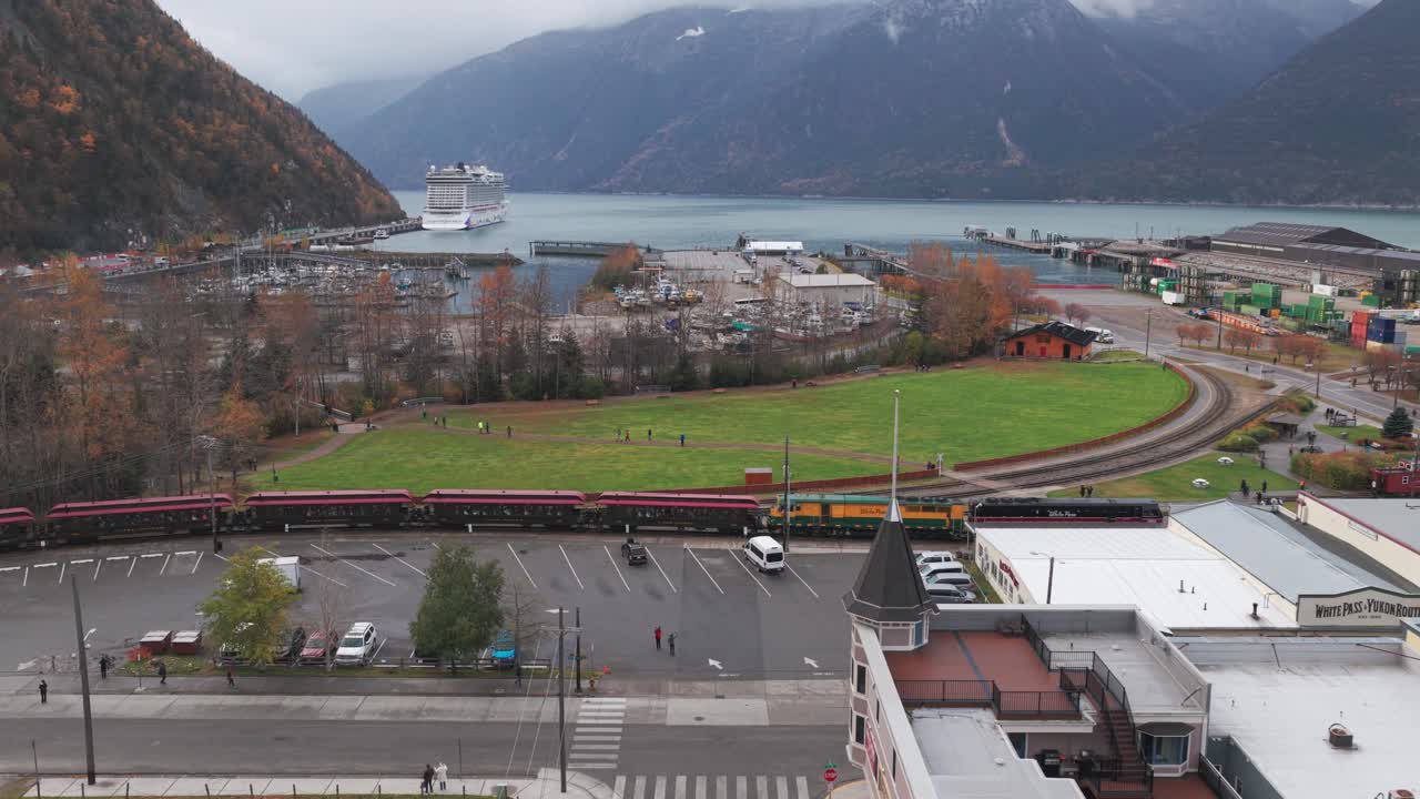 White panning aerial shot of the White Pass Yukon Route train arriving at the station during autumn in Skagway, Alaska. 4K