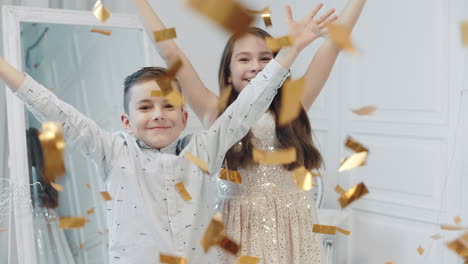 Portrait-of-happy-children-throwing-golden-confetti-into-camera.