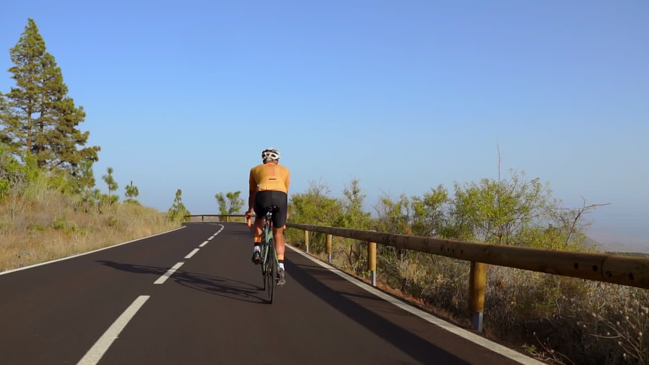 With the road all to himself, a man rides his road bike during the morning, embracing outdoor exercise. The slow-motion portrayal heightens the spirit of extreme sports
