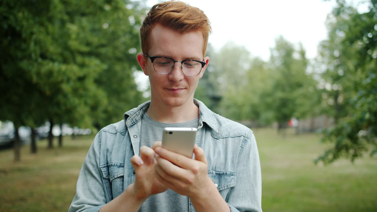 Giovane uomo che usa lo smartphone in un parco