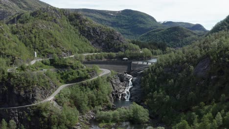 Toma-Aérea-Ascendente-Sobre-La-Presa-Con-Caminos-Sinuosos-En-El-Valle-De-Las-Montañas-Noruegas