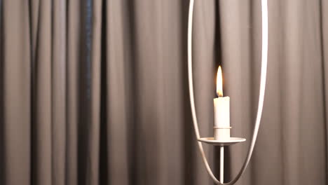 Slow-slide-shot-of-smoke-rising-by-lit-candle-hanging-on-holder-inside