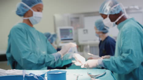 nurse hands surgeon medical instruments as surgical team work on patient in operating theatre