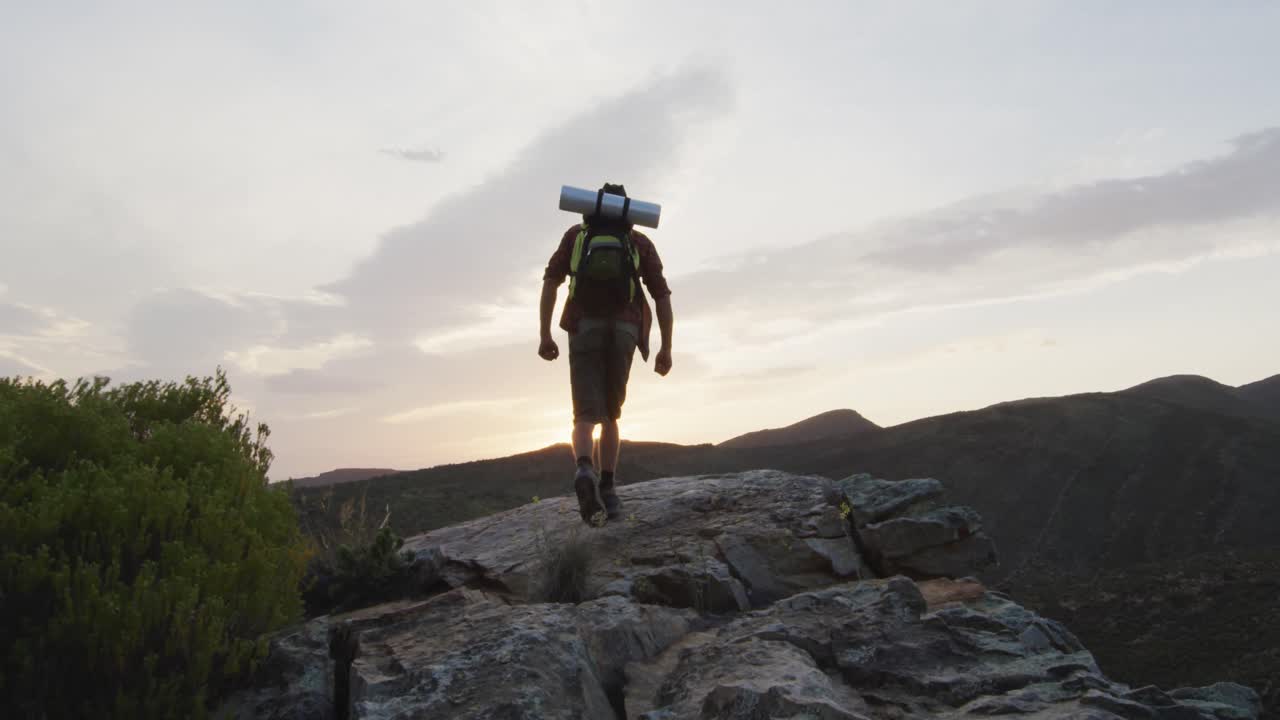 sobreviviente caucásico con los brazos en el aire, celebrando alcanzar el pico de la montaña en el desierto