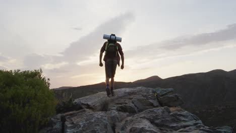 Superviviente-Masculino-Caucásico-Con-Los-Brazos-En-El-Aire,-Celebrando-Alcanzar-La-Cima-De-La-Montaña-En-El-Desierto