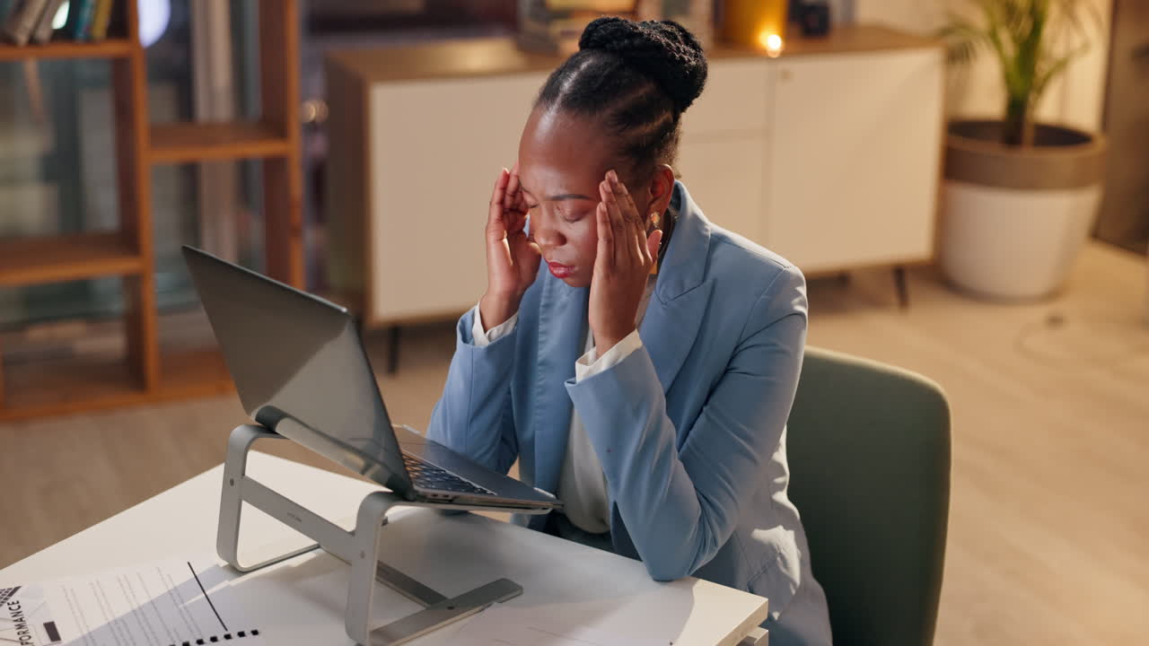 Woman with headache at laptop in the office
