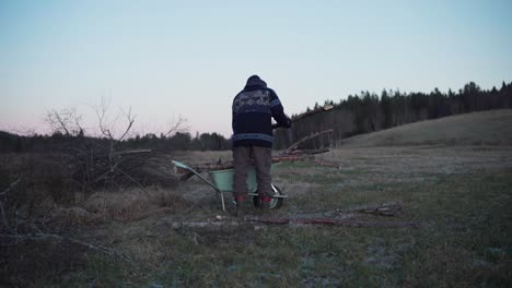a man is placing the logs into the wheelbarrow - static shot
