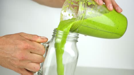 pouring a nutritious green smoothie into a fun mason jar