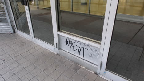 graffiti on a closed storefront window with tiled pavement in market east, philadelphia.