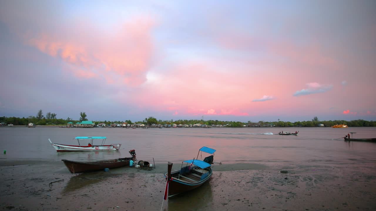 una hermosa vista del río pak nam en krabi, tailandia, con una puesta de sol rosada y nublada y botes de cola larga