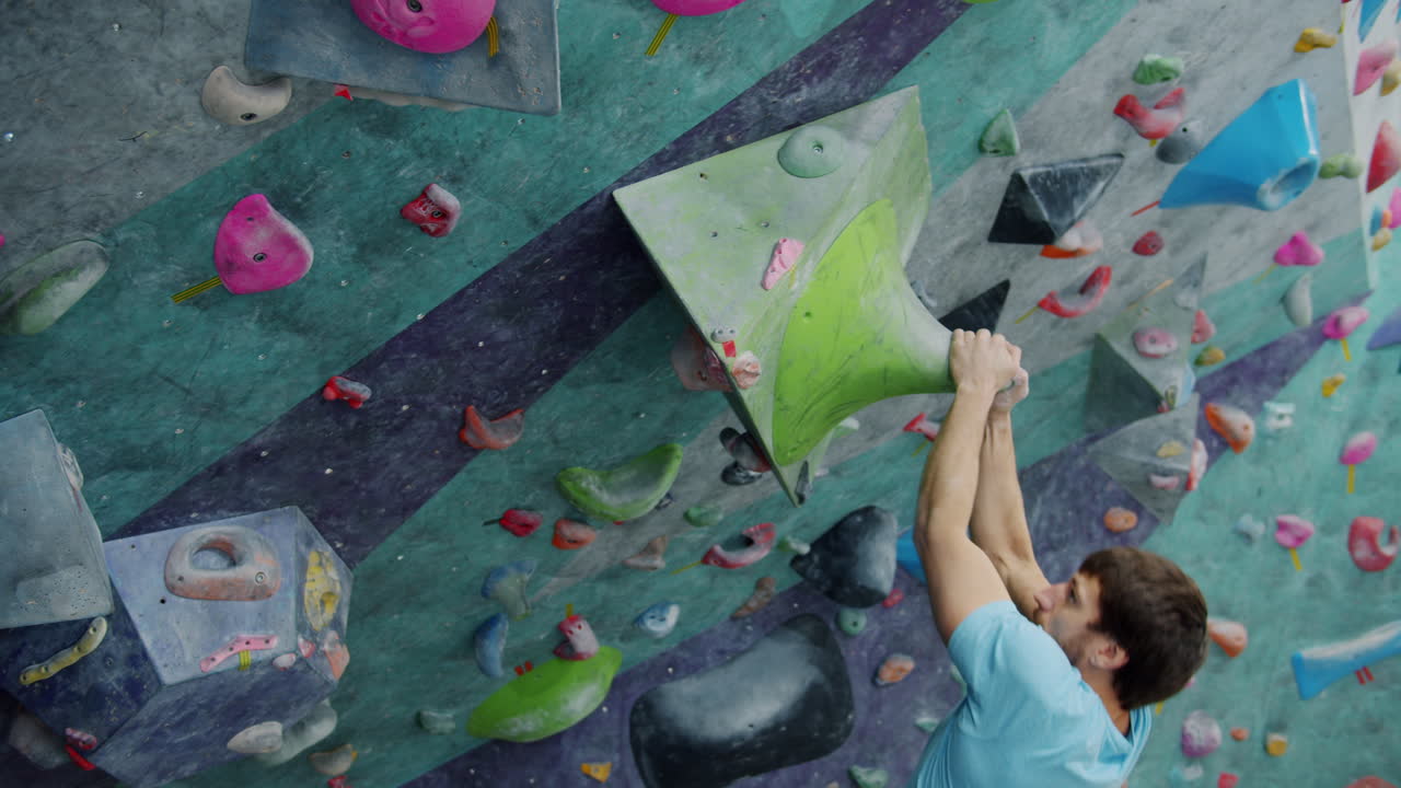 hombre escalando roca en la pared de escalada interior