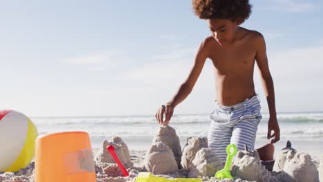 hermano y hermana afroamericanos jugando con arena en la playa