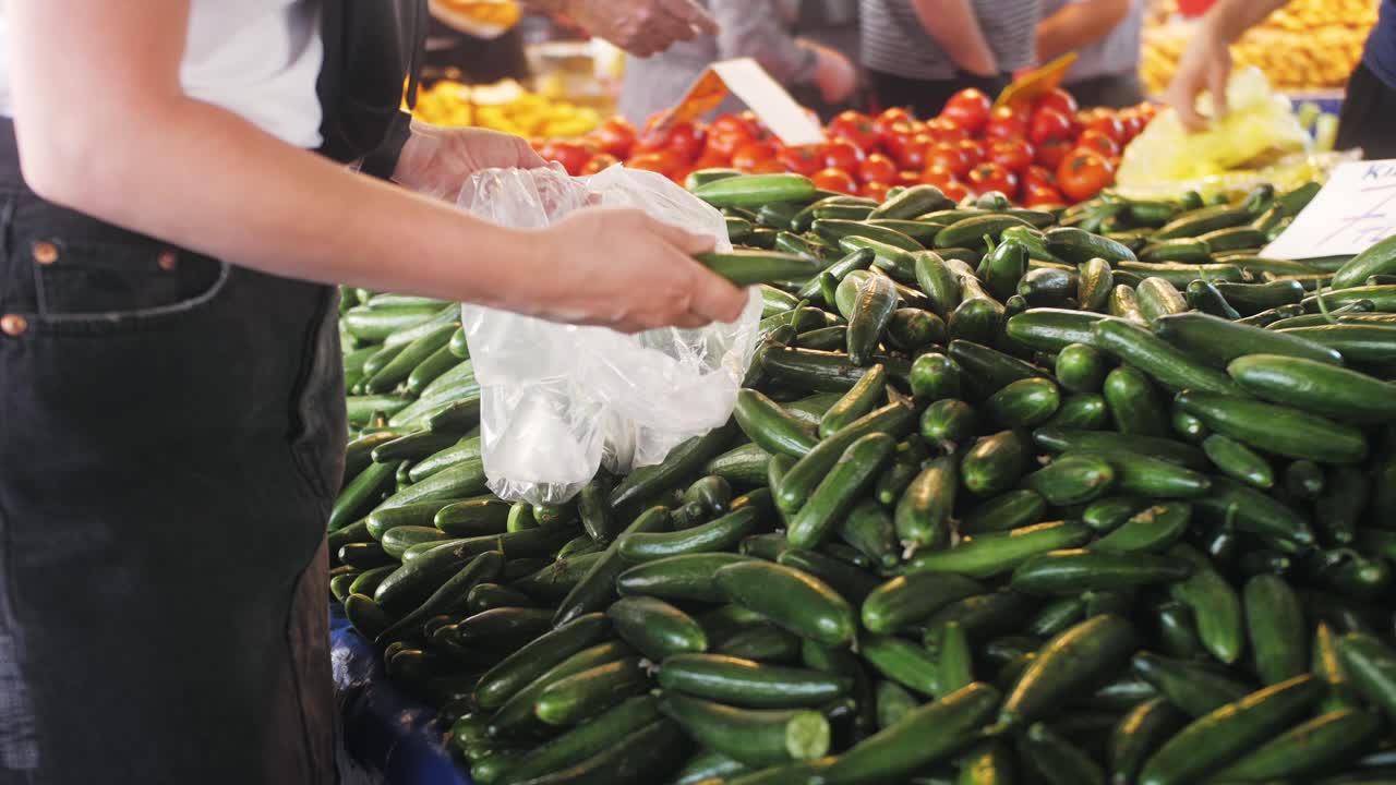 mujer comprando pepinos en un mercado