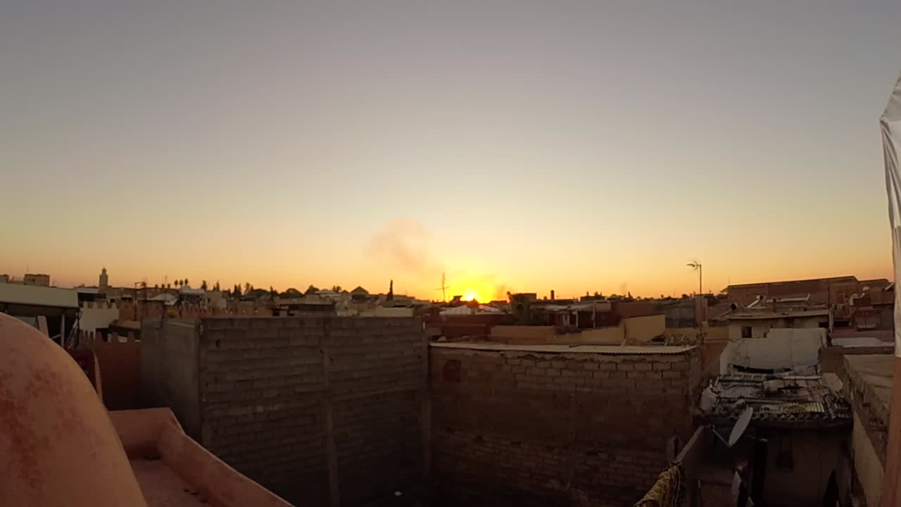 Time-lapse del tramonto su quadrante rotante che gira a sinistra, ripreso dall'alto sui tetti e sulla medina di Marrakech, Marocco, all'ora d'oro