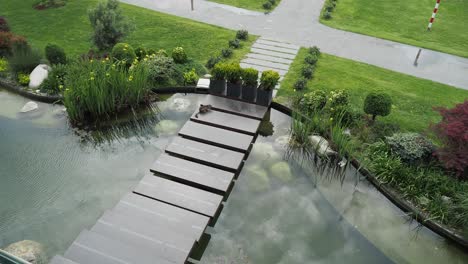 a cat walks across a stone bridge over a pond