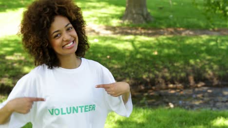 voluntario muy sonriendo a la cámara y apuntando a la camiseta