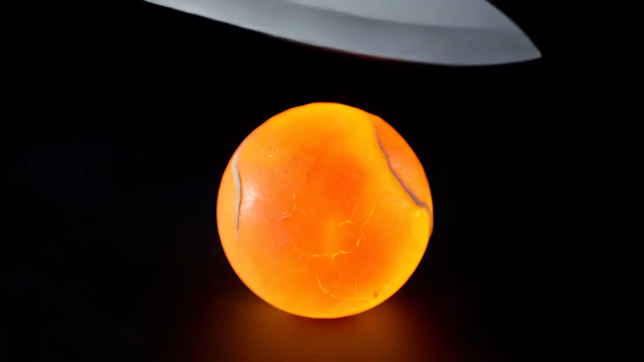 Knife Cutting Through Cracking Spherical Objects