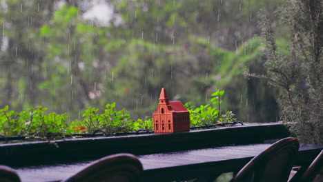 outdoor balcony adorned with flowers and clay church model decor in rainy day